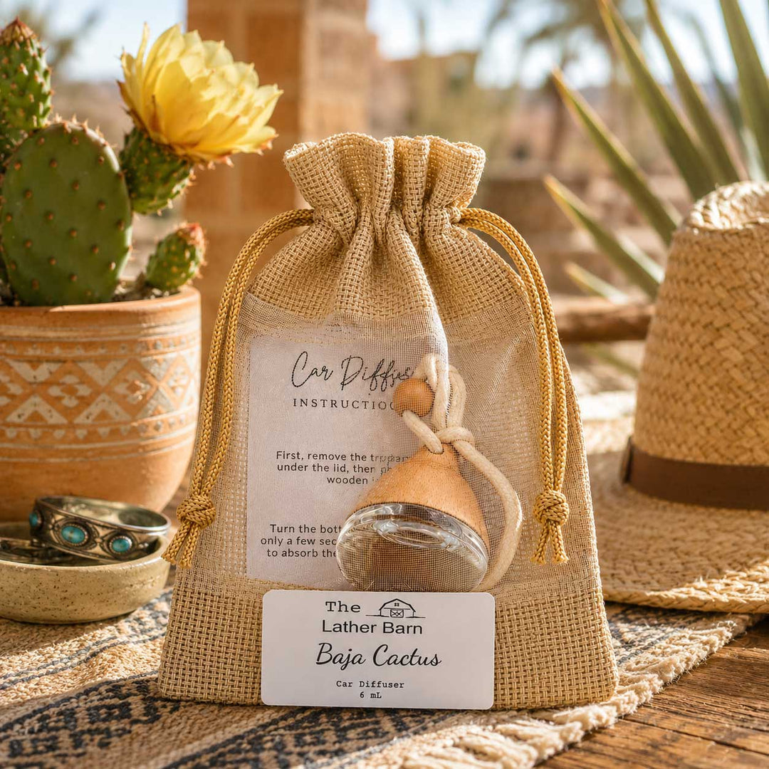 A small clear mesh drawstring pouch with a tan burlap trim sits on a woven rug in a styled outdoor setting. Inside the pouch is a small glass bottle with a wooden stopper and a printed instruction card.