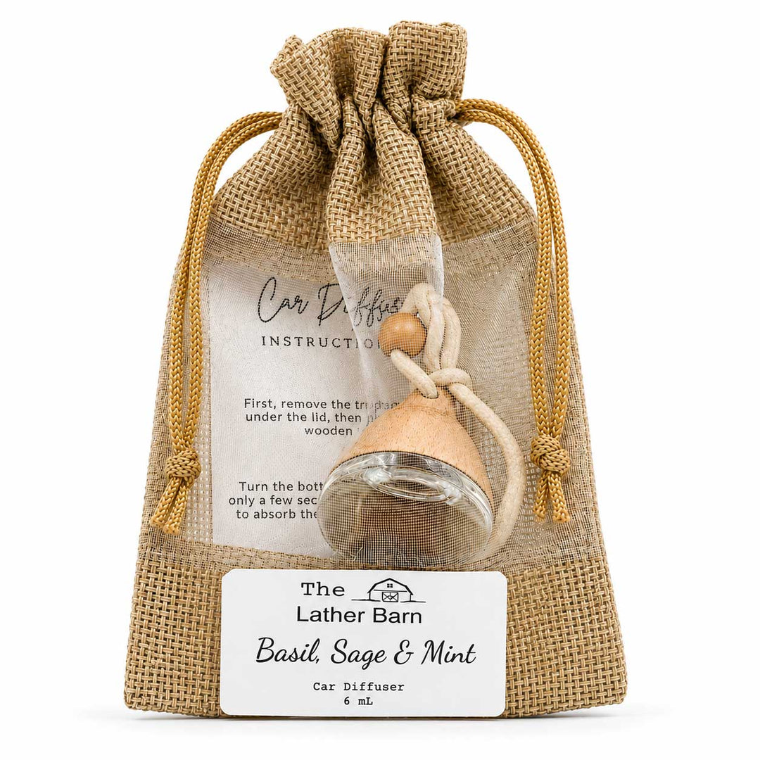 A car diffuser in clear plastic packaging inside a burlap drawstring pouch, with an instruction card and a white label reading 'The Lather Barn Basil, Sage & Mint Car Diffuser 6 ml'.