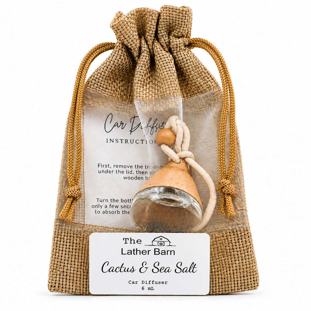 A car diffuser bottle with a wooden stopper and beige cord, presented inside a burlap drawstring pouch with a white instruction card and a front label reading 'The Lather Barn Cactus & Sea Salt Car Diffuser 6 mL'.