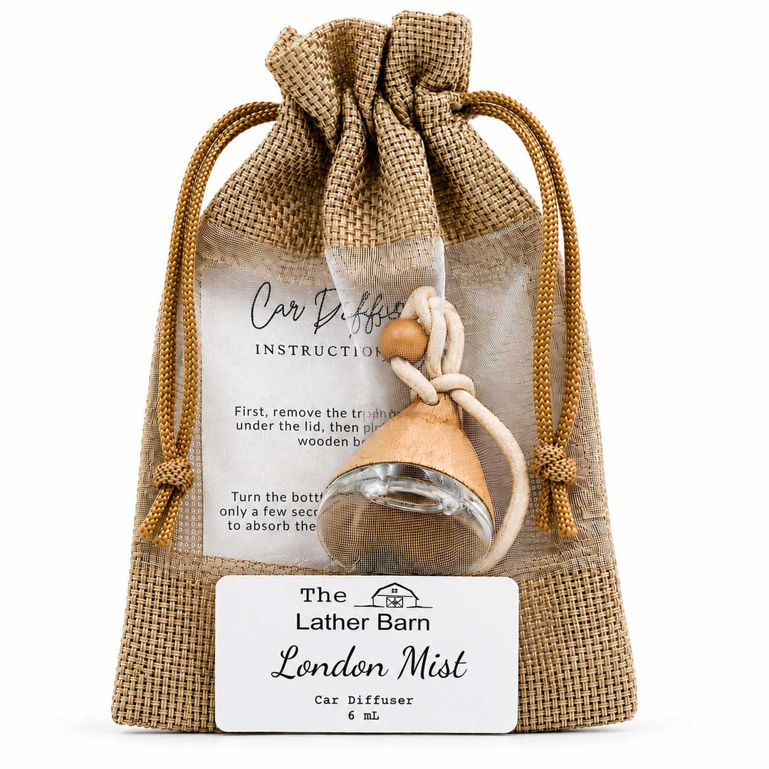 A small car diffuser bottle with a beige wooden diffuser top and white cord, presented inside a clear drawstring burlap pouch with printed instructions and a front label reading 'The Lather Barn London Mist Car Diffuser 6 mL'.