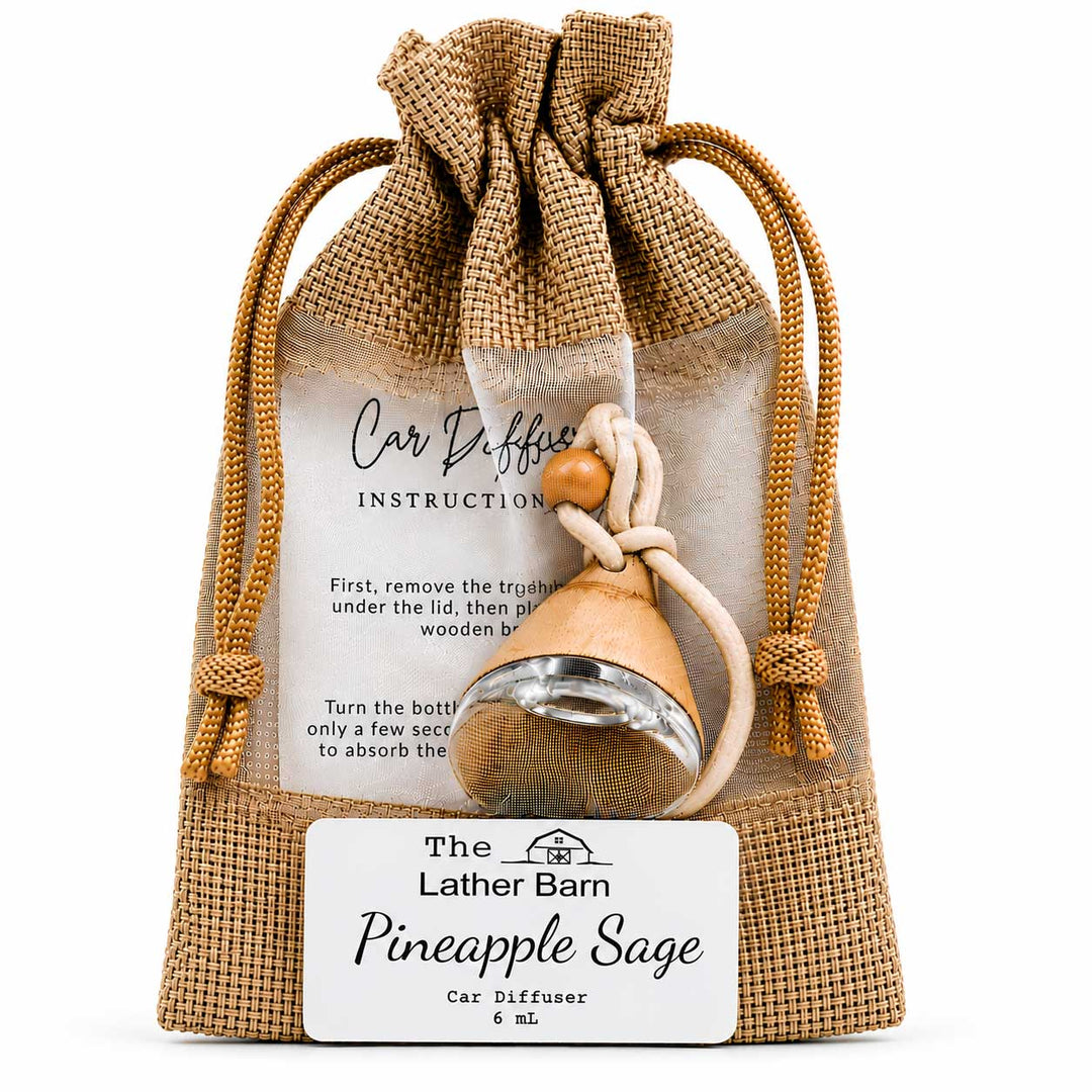 A pine-sage scented car diffuser bottle with a wooden handle and metal mesh filter, presented inside a burlap drawstring pouch with an instruction card and a front label reading 'The Lather Barn Pineapple Sage Car Diffuser 6 mL'.