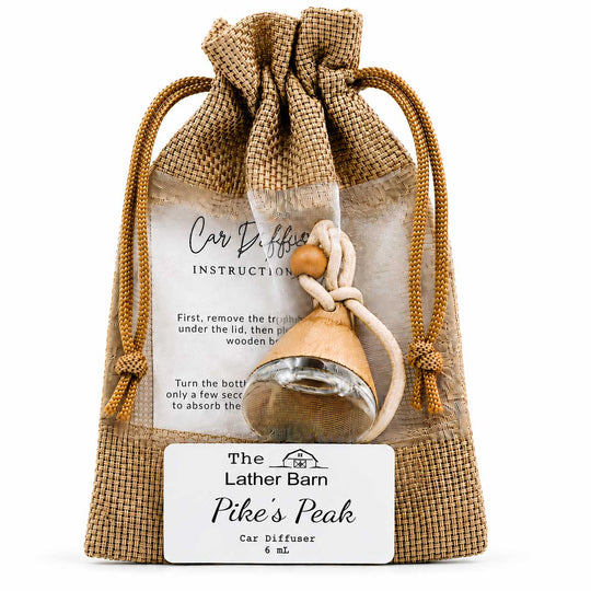 A packaged car diffuser set from The Lather Barn named Pike's Peak, featuring a small wooden diffuser bottle inside a clear bag with a burlap drawstring pouch and a white instruction card.