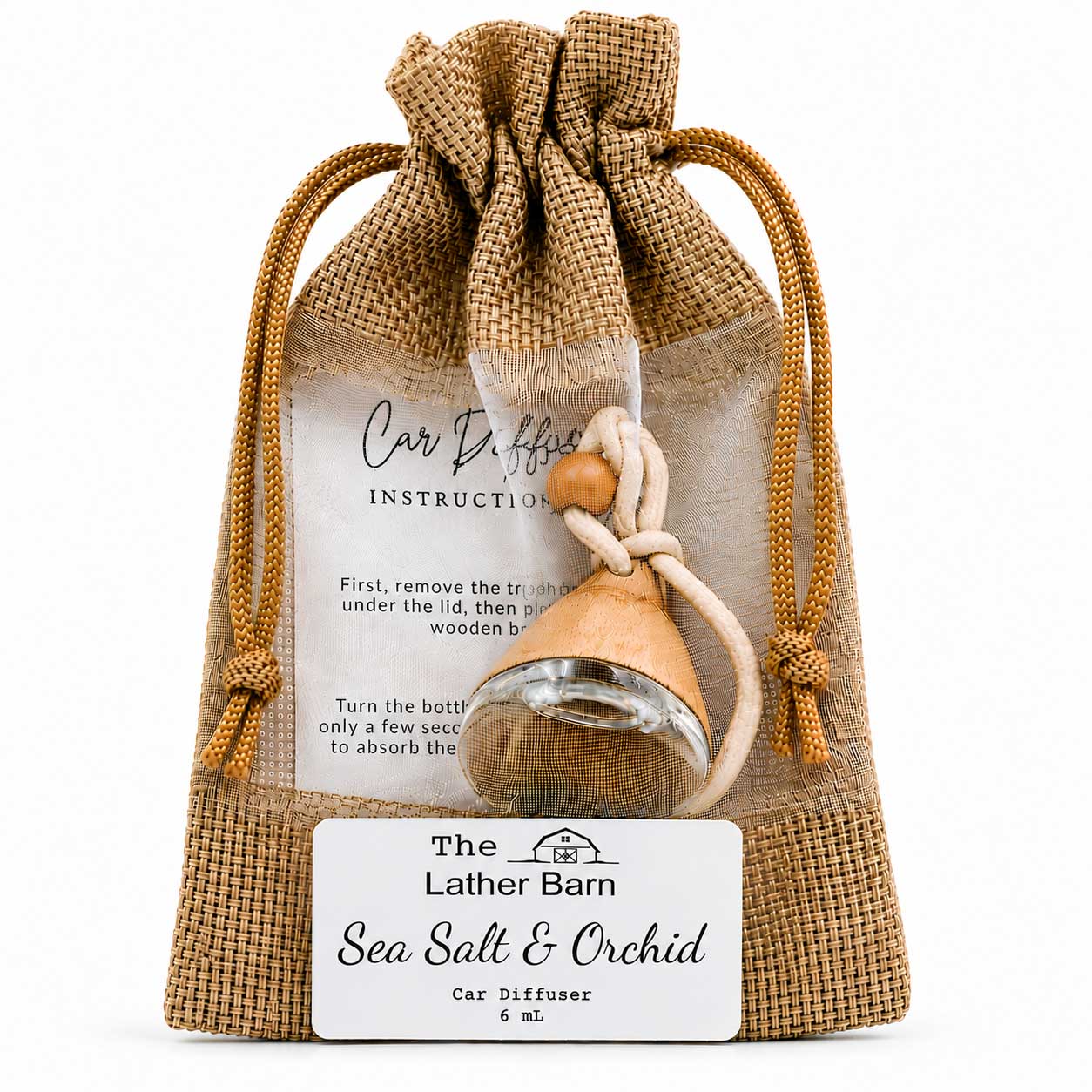 A car diffuser in a clear drawstring pouch with burlap trim, labeled 'The Lather Barn Sea Salt & Orchid Car Diffuser 6 mL.' A small wooden diffuser bottle with a rope tie and clear glass bowl is visible through the pouch, with an instruction card behind it on a white background.