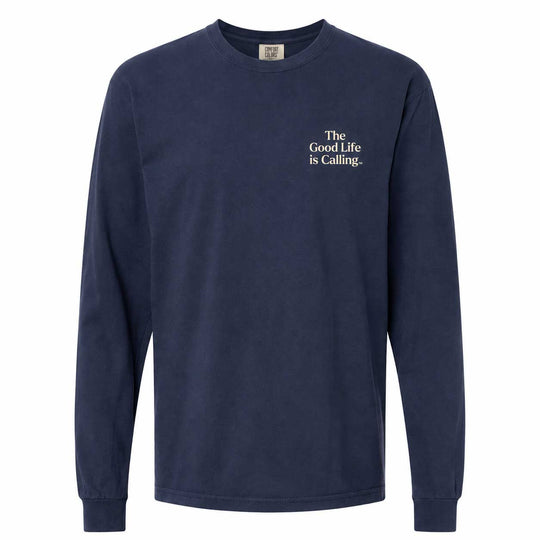 A navy blue long-sleeve crewneck t-shirt with white text on the left chest reading 'The Good Life is Calling.' on a plain white background.