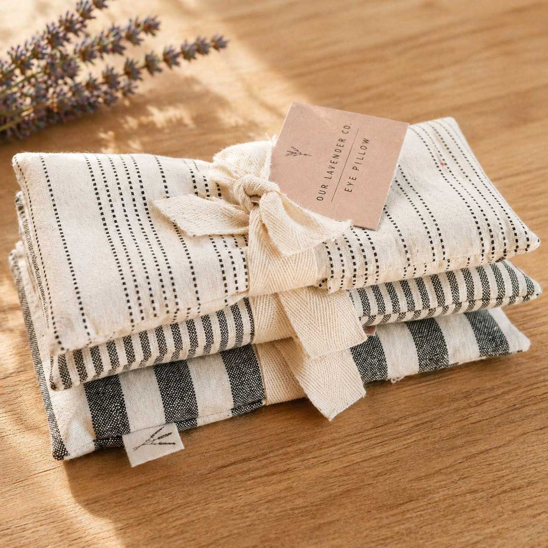 Stack of striped eye pillows with a card on a wooden surface