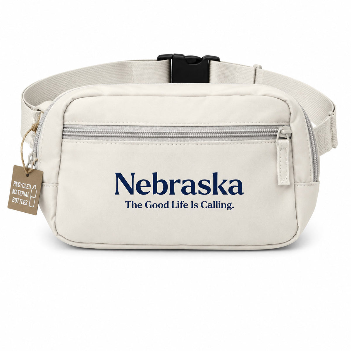An off-white nylon fanny pack with a navy blue printed logo reading 'Nebraska The Good Life Is Calling.' on the front, featuring a black plastic buckle and a brown 'Recycled Materials Pledged' tag on the side.