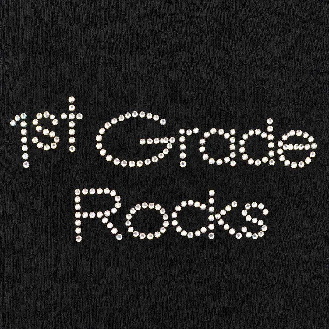 White rhinestone lettering that reads '1st Grade Rocks' on a black fabric background.