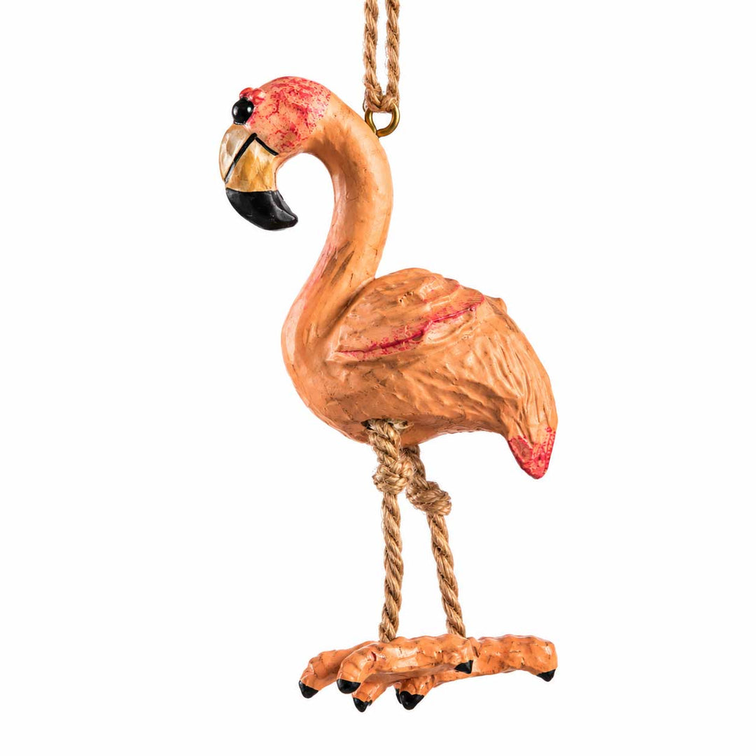 A decorative flamingo hanging ornament in a warm peach-pink color with red accents, a black and gold beak, and rope-wrapped legs, shown against a plain white background.