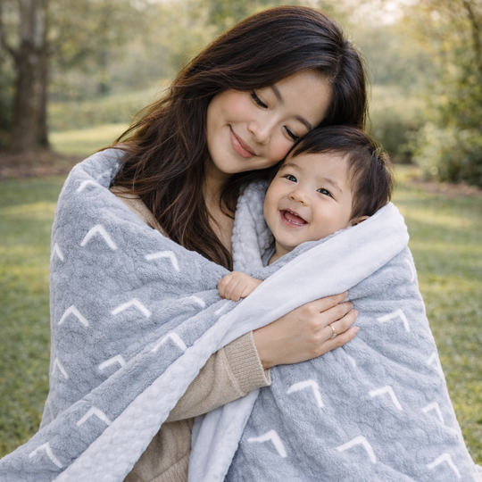 Woman and child wrapped in a gray patterned blanket outdoors