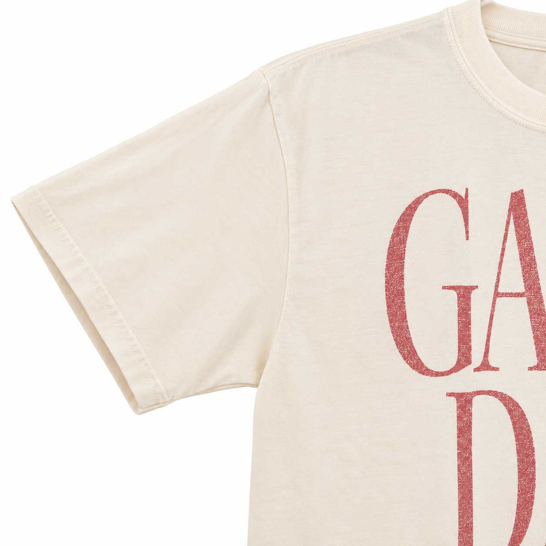 Close-up of an off-white short-sleeve T-shirt with a distressed red graphic print reading 'GARD' on the front, shown against a plain white background.