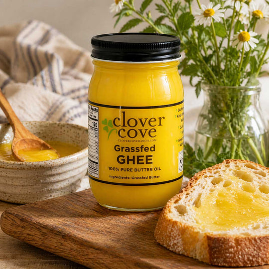 Jar of clover cove grassfed ghee on a wooden board with bread and flowers in the background
