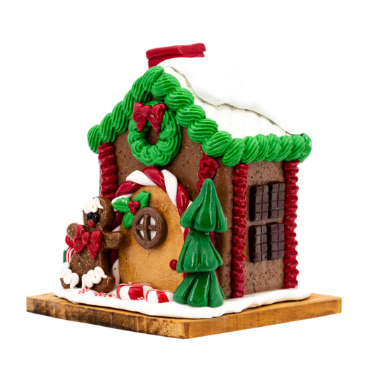 Decorative gingerbread house with green roof, red trim, and candy decorations on a white background