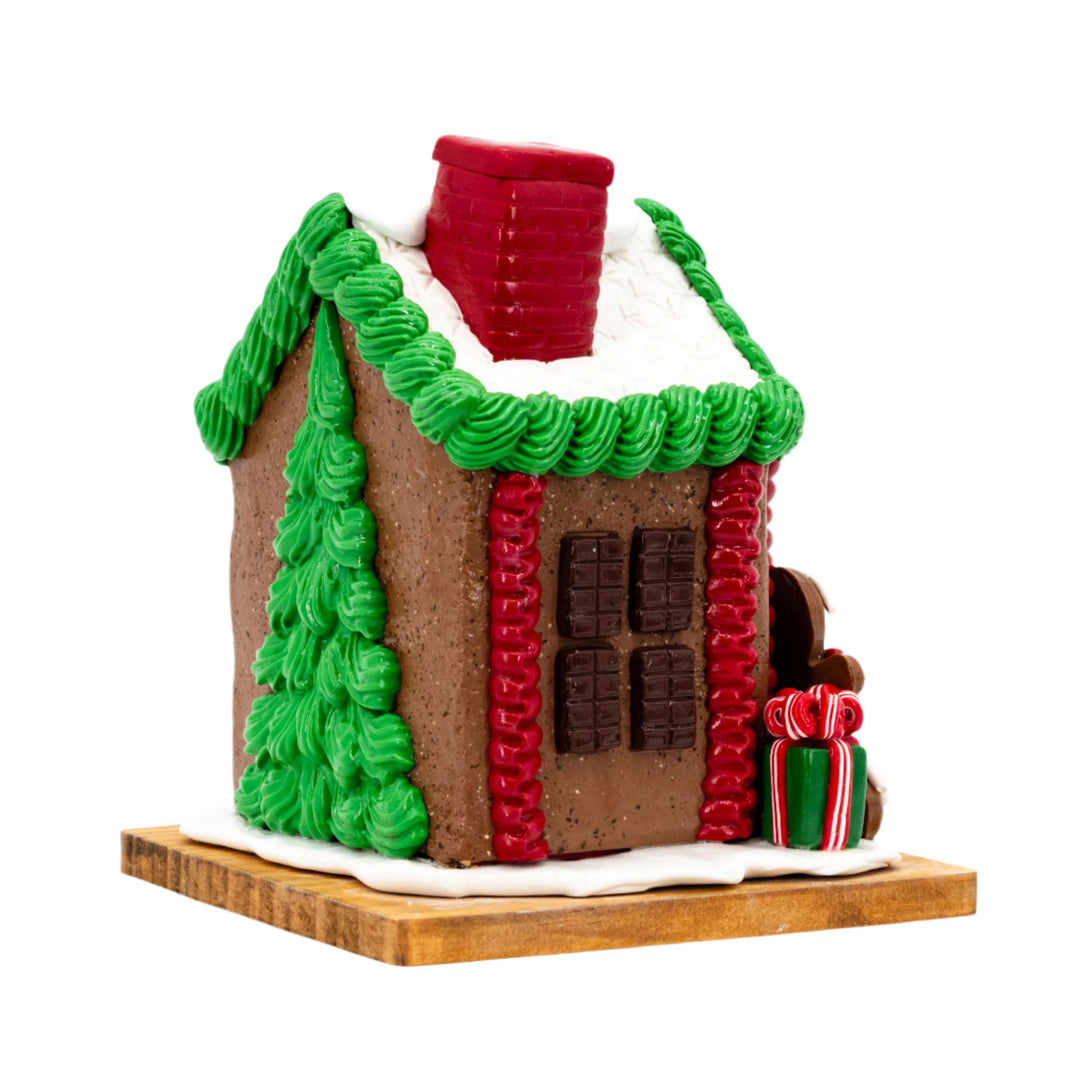 Gingerbread house with green roof, red chimney, and decorative elements on a white background