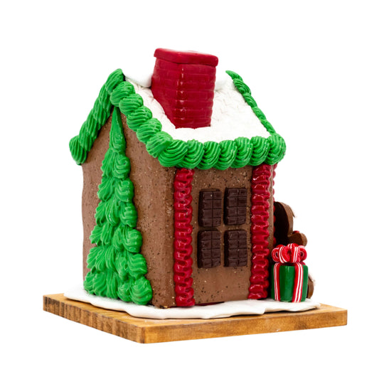 Gingerbread house with green roof, red chimney, and decorative elements on a white background