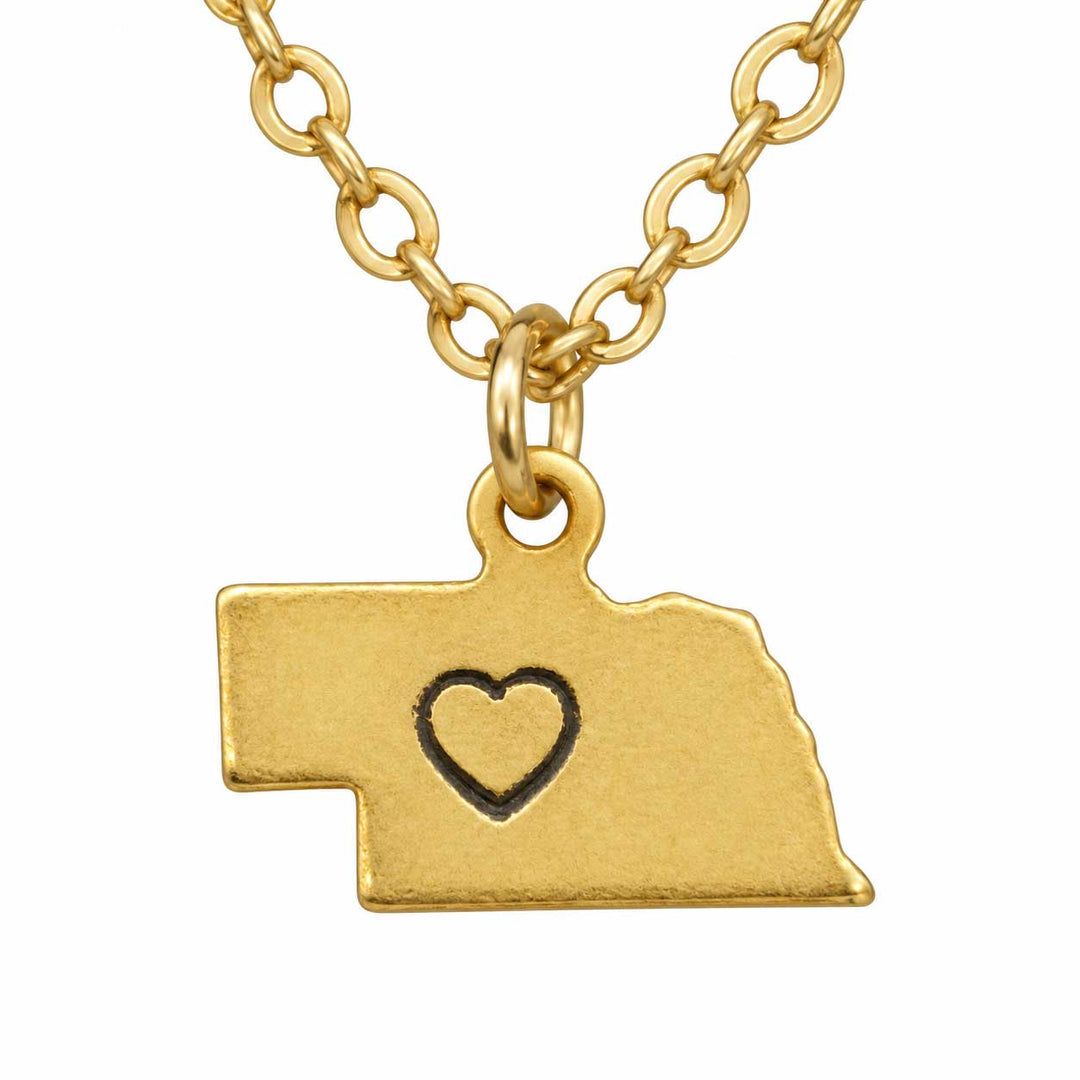 Gold necklace with a pendant shaped like the state of Nebraska, featuring a cutout heart in the center, on a white background.