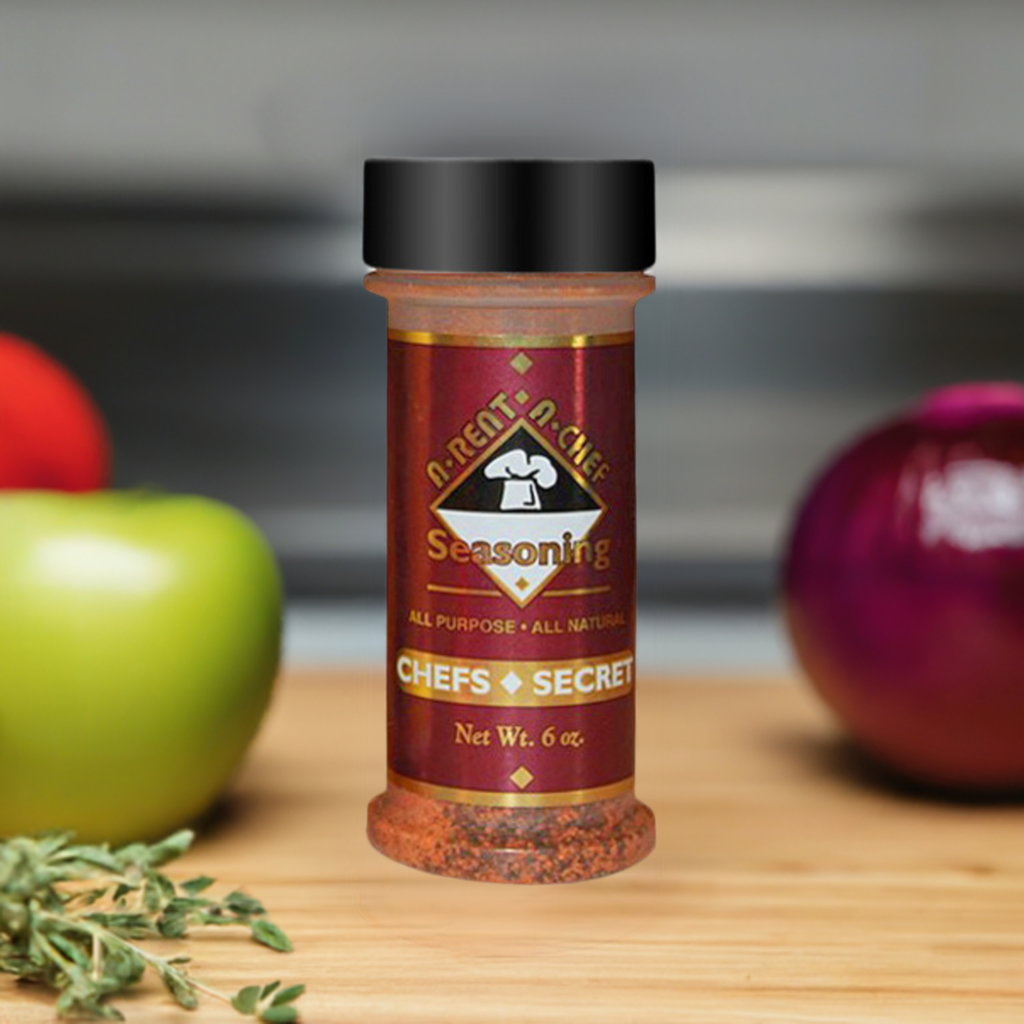 One bottle of Chef's Secret All Purpose Seasoning On A Table Surrounded By Vegetables and Herbs.