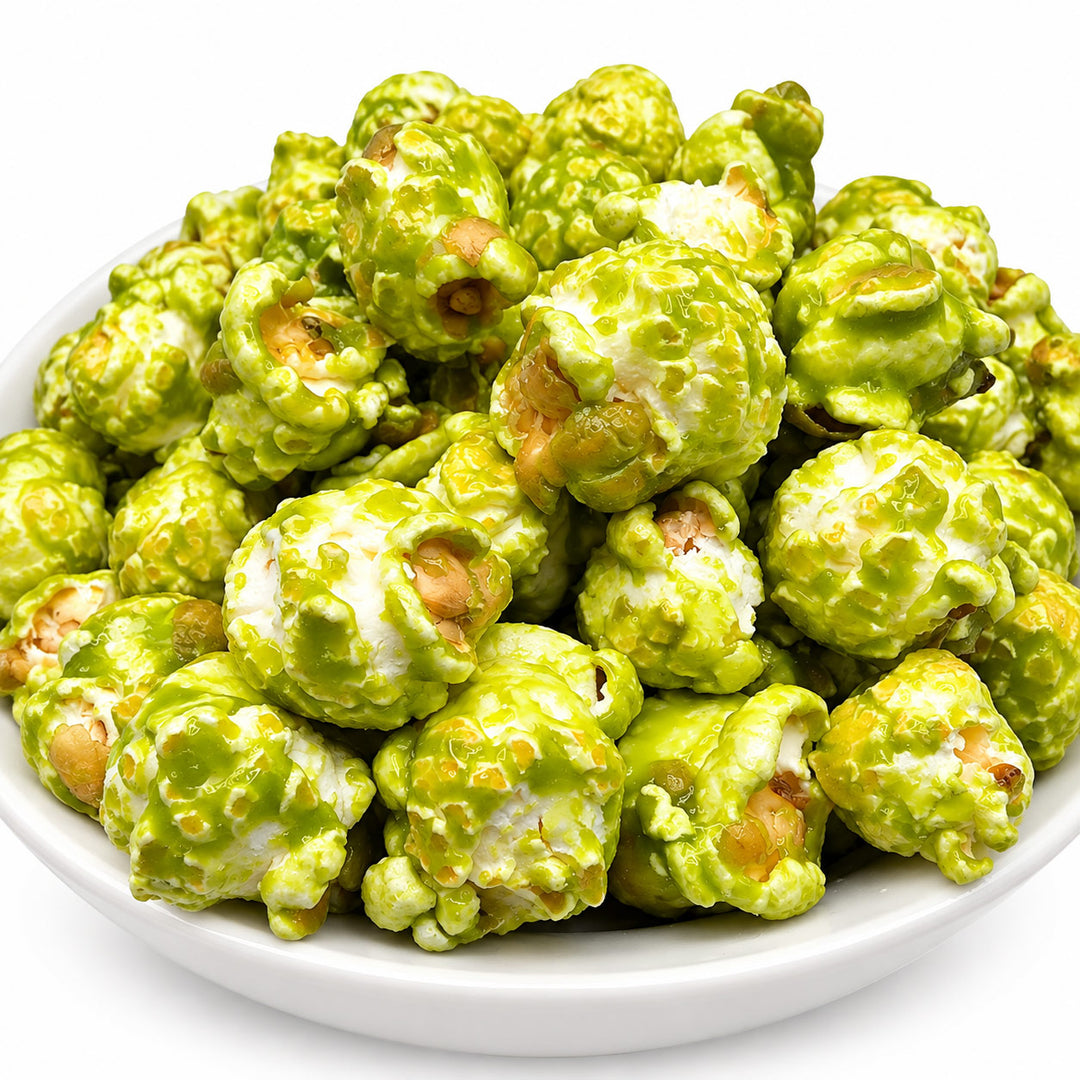 Green popcorn coated in a glossy lime-green sauce, piled in a white bowl against a clean white background.