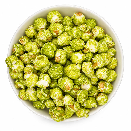 Green popcorn coated in white sauce, served in a white bowl on a white background.