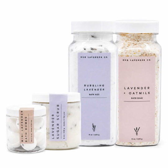 Set of lavender-themed bath products including a jar, bath fizz, and soap on a white background.