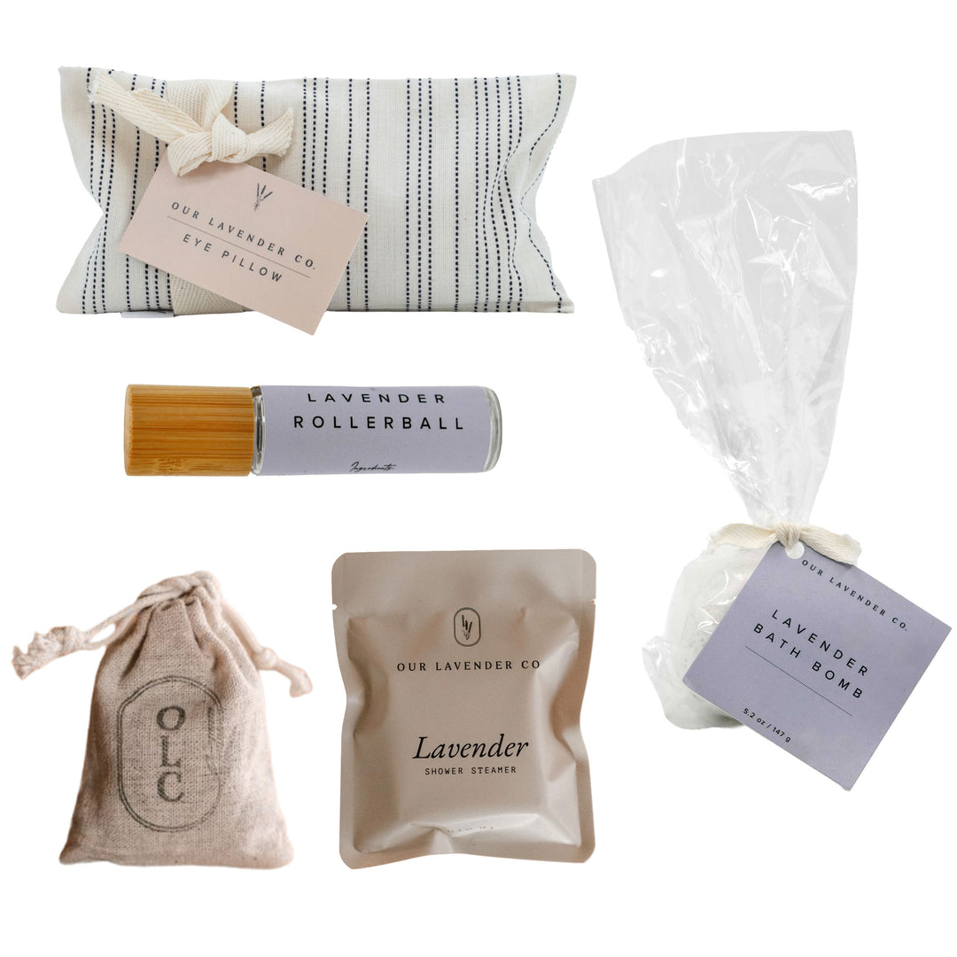 Collection of lavender-themed products including a eye pillow, rollerball, bath bomb, and shower decal on a white background.