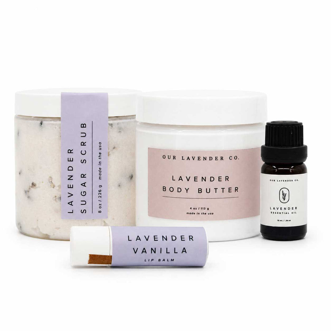Set of lavender-themed skincare products including scrub, body butter, lip balm, and essential oil on a white background.
