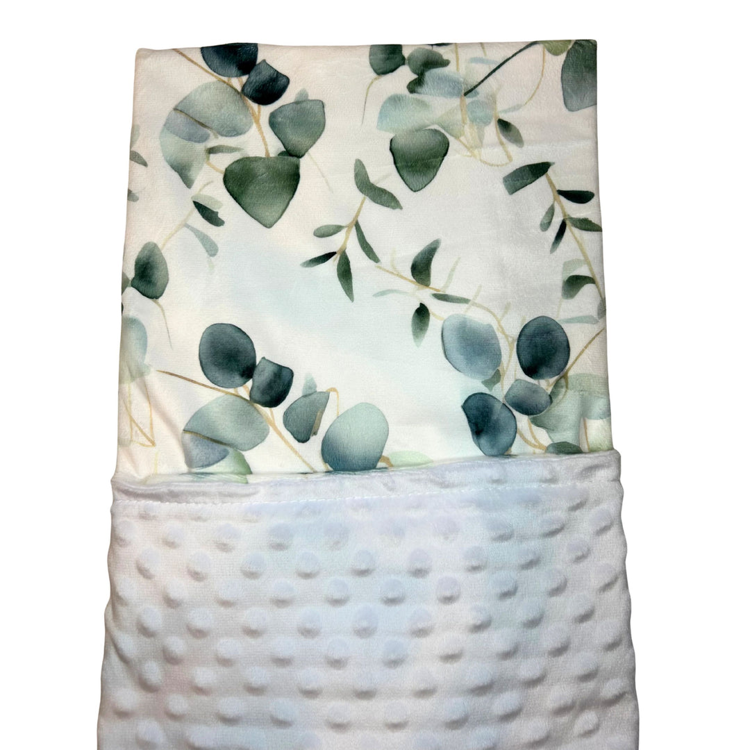 Towel with eucalyptus leaf pattern in a textured basket on a white background