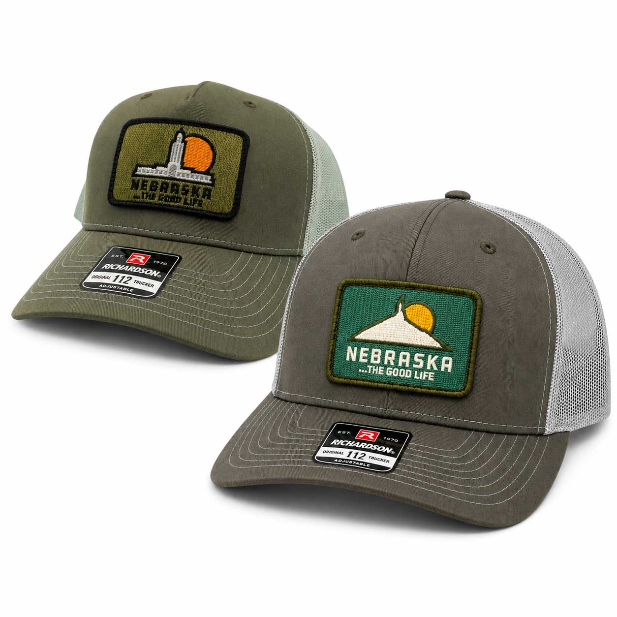 Two Nebraska trucker hats on a white background, one in olive green and one in gray. Both feature a rectangular patch with the Nebraska state silhouette and sun, and a visible Richardson 112 size 72 size label on the brim.