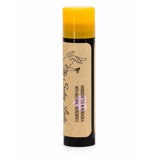 Lip balm with a yellow cap and brown label on a white background