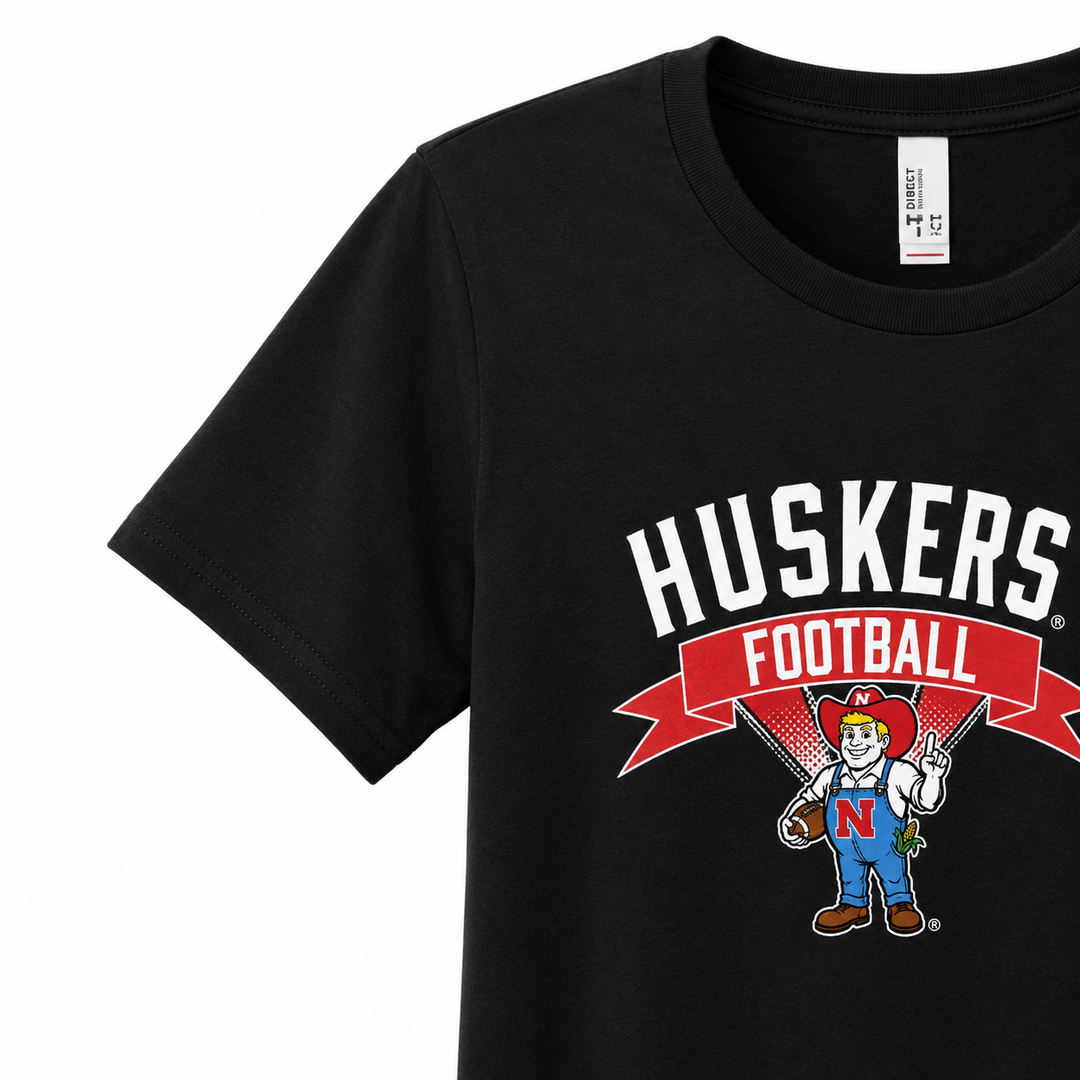 Black t-shirt with 'Huskers Football' design featuring a mascot and banner on a white background