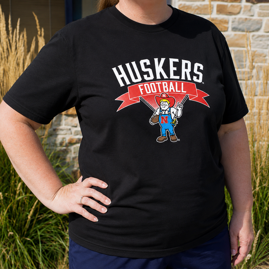 Person wearing a black t-shirt with 'Huskies Football' design outdoors.