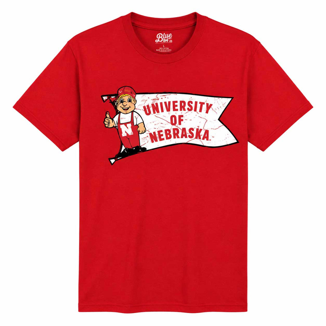 A red short-sleeve crewneck t-shirt featuring a University of Nebraska graphic on the chest, including the mascot Nebraskan and a banner reading 'UNIVERSITY OF NEBRASKA'.