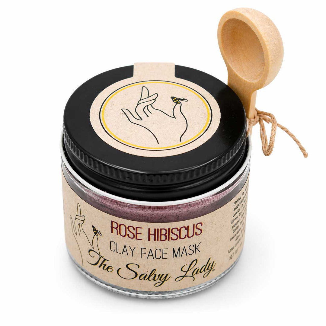 Jar of Rose Hibiscus Clay Face Mask with a wooden scoop on a white background