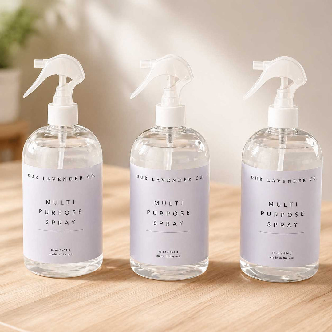 Three bottles of 'Our Lavender Co.' multi-purpose spray on a wooden surface.