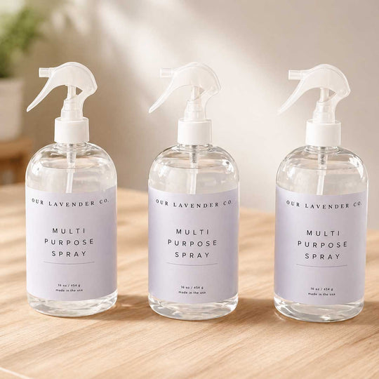 Three bottles of 'Our Lavender Co.' multi-purpose spray on a wooden surface.
