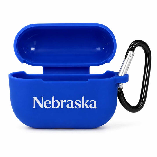 A royal blue silicone AirPods case with the word 'Nebraska' printed in white across the front, shown open with a black carabiner attached on the side, against a plain white background.