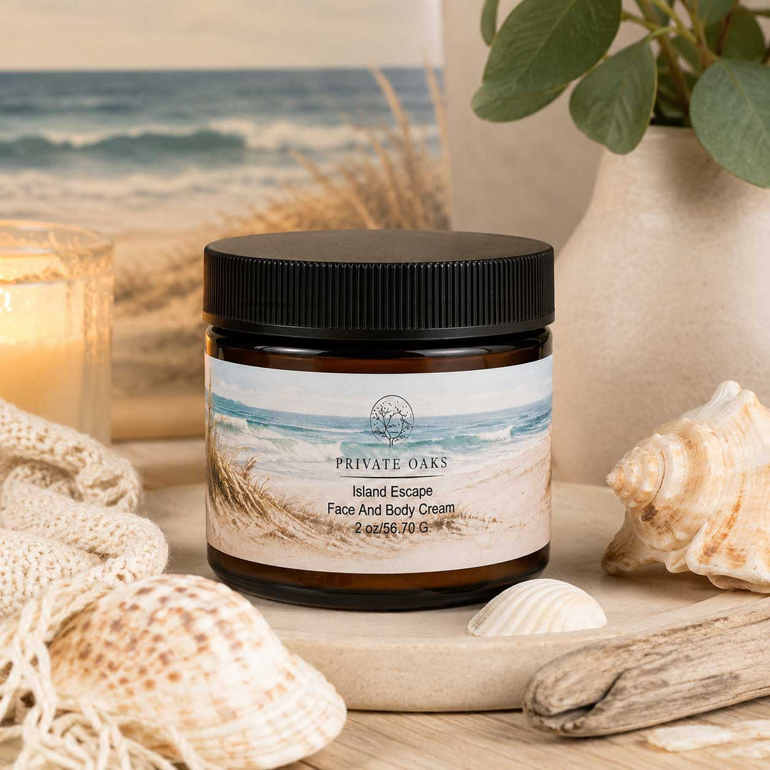 A jar of Private Oaks Island Escape Face And Body Cream sits on a wooden board surrounded by seashells, driftwood, a candle, and a beach scene backdrop.