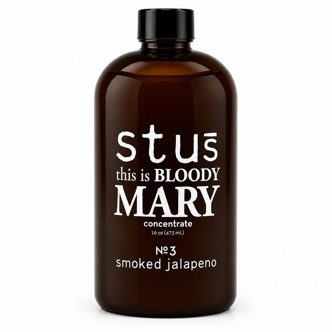 An amber glass bottle with a black cap, featuring white text that reads 'stús this is BLOODY MARY concentrate' and 'N°3 smoked jalapeno' on a plain white background.