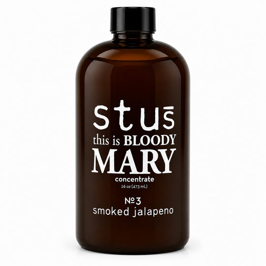 An amber glass bottle with a black cap, featuring white text that reads 'stús this is BLOODY MARY concentrate' and 'N°3 smoked jalapeno' on a plain white background.
