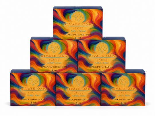 Six boxes of Private Oak Laced Handcrafted Bar Soap arranged in a pyramid stack on a white background. The packaging features a vibrant, multicolored abstract swirl pattern in orange, yellow, red, blue, and green with a gold circular tree logo and gold text.