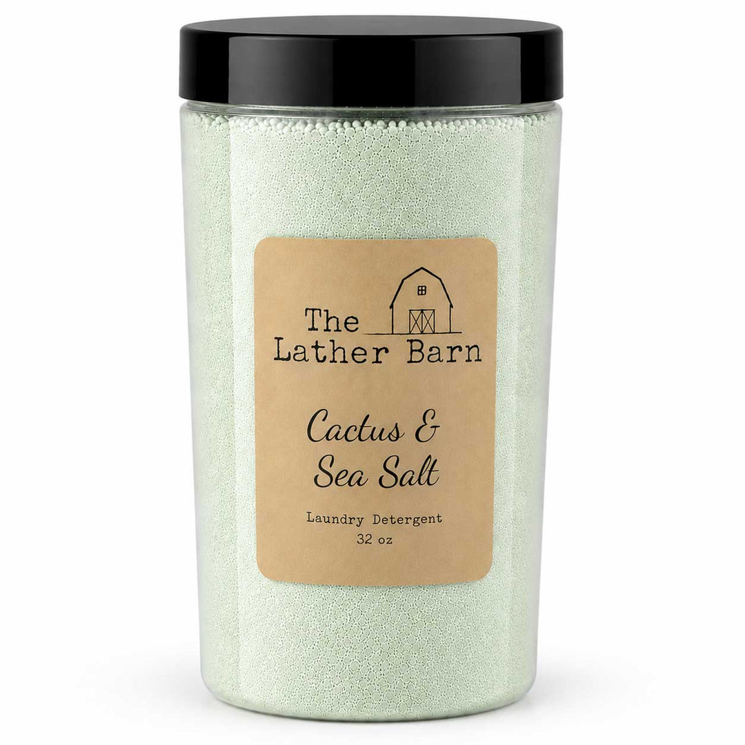 A 32 oz jar of The Lather Barn Cactus & Sea Salt laundry detergent. The product consists of pale green sea salt granules inside a clear plastic jar with a black lid and a tan paper label.