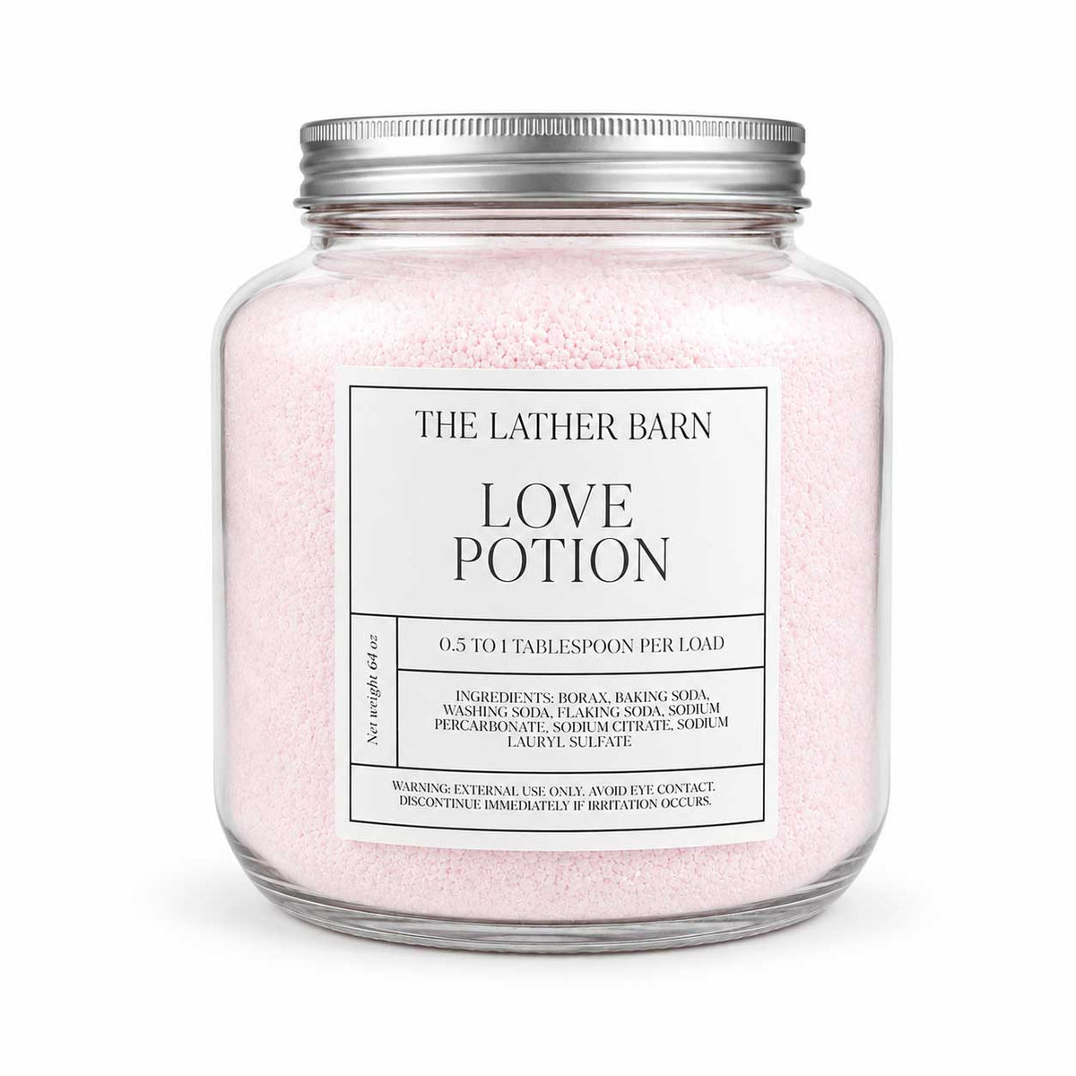 A glass jar candle filled with pale pink bath-like granules, topped with a silver metal lid, and labeled 'THE LATHER BARN LOVE POTION' on a white background.