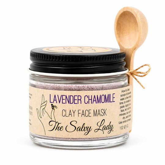Jar of lavender chamomile clay face mask with a wooden spoon on a white background