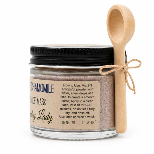 Jar of chamomile face mask with a wooden spoon on a white background