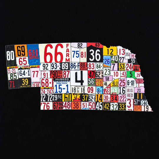 A state-shaped wall art piece made from many vintage license plates in different colors and patterns, shown on a solid black background.