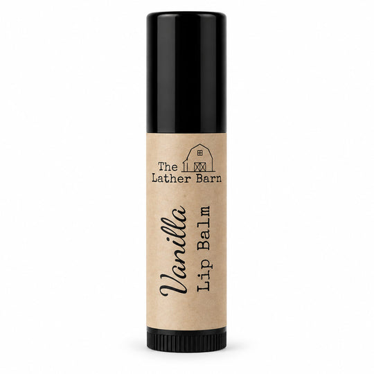A single tube of Vanilla Lip Balm by The Lather Barn, featuring a natural kraft paper label and a black cap, set against a plain white background.