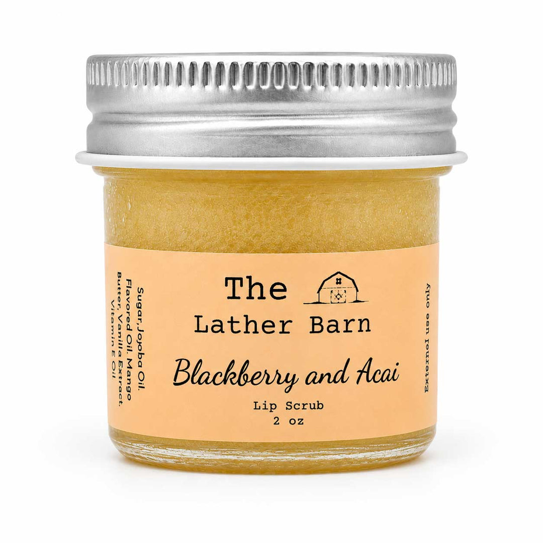 A 2 oz glass jar of The Lather Barn Blackberry and Acai Lip Scrub, filled with a golden-yellow scrub and topped with a silver metal screw cap, set against a plain white background.