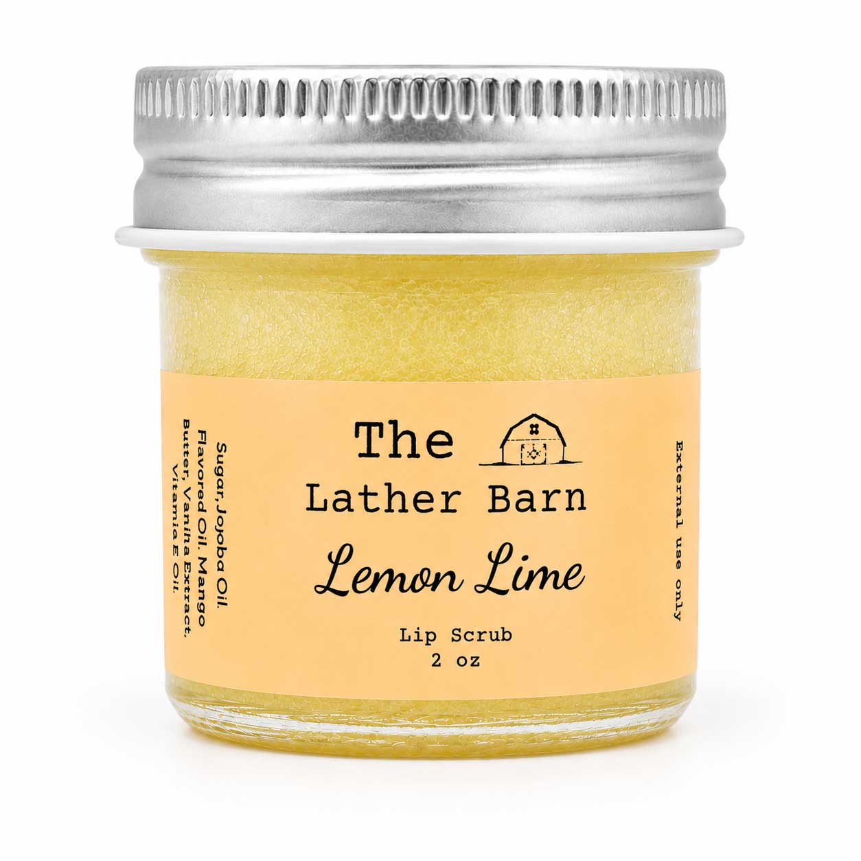 A 2 oz glass jar of The Lather Barn Lemon Lime Lip Scrub, filled with a pale yellow-green scrub and featuring a light peach label with a silver metal screw lid, set against a plain white background.