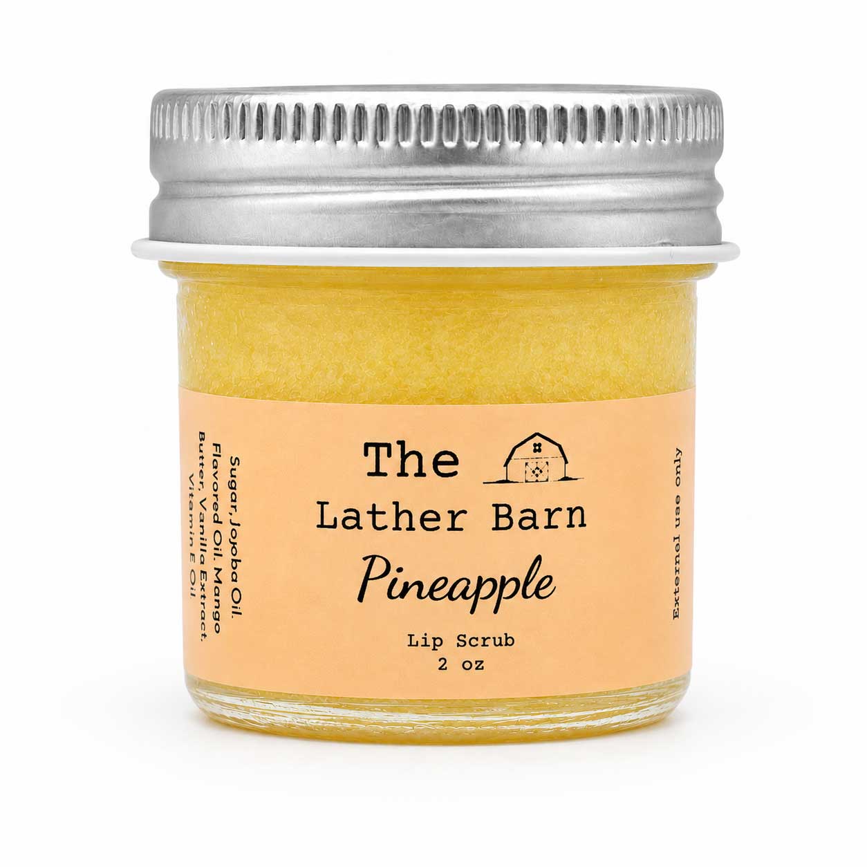 A 2 oz glass jar of The Lather Barn Pineapple Lip Scrub, filled with a pale yellow scrub and featuring a peach-colored label and a silver metal screw cap, set against a plain white background.