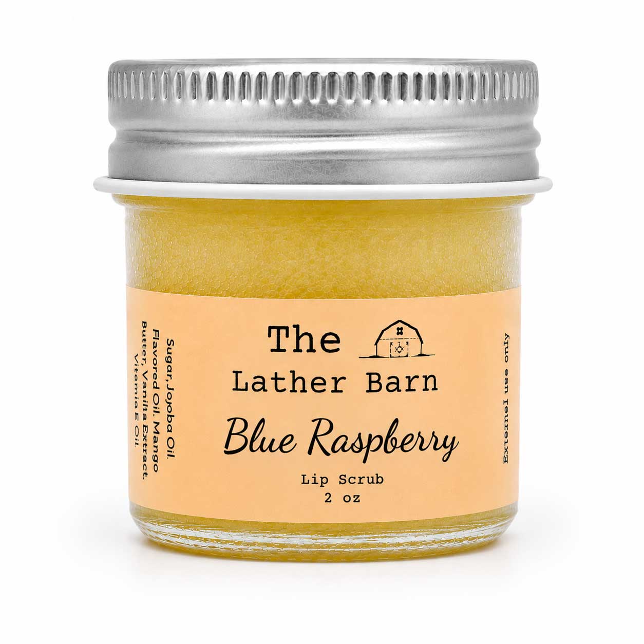 A small glass jar of The Lather Barn Blue Raspberry lip scrub, filled with a pale yellow scrub and topped with a silver metal lid, set against a plain white background.