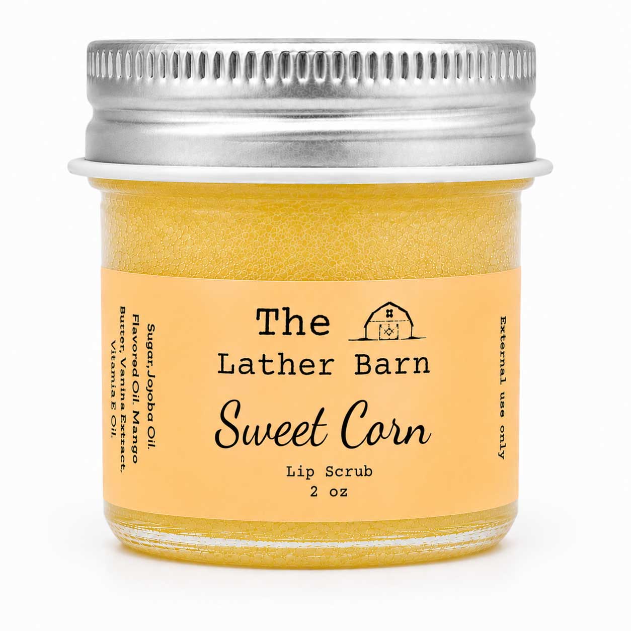 A 2 oz glass jar of The Lather Barn Sweet Corn Lip Scrub, filled with a golden yellow scrub and featuring a light peach label with a silver metal screw lid, set against a plain white background.